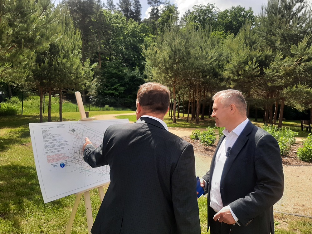 Dwóch mężczyzn omawia plan projektowy nowej inwestycji sportowej w Rumi przy sztaludze w parku