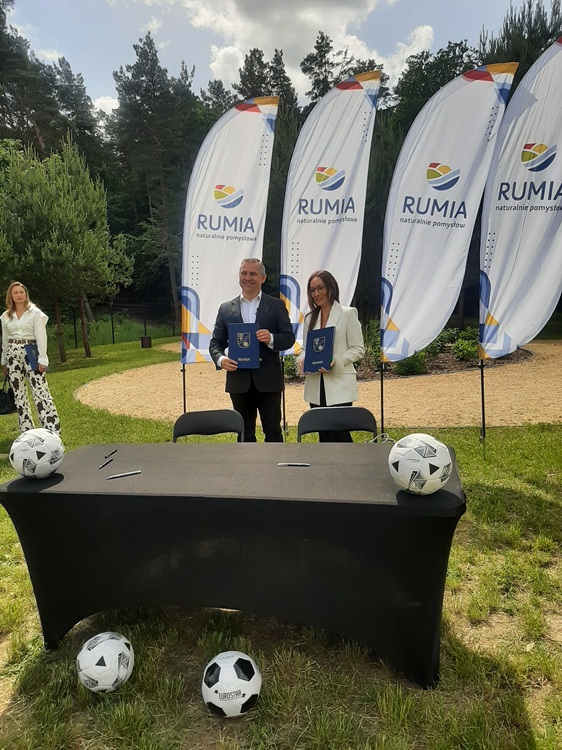 Burmistrz Michał Pasieczny i przedstawicielka firmy wykonawczej wymieniają uścisk dłoni po podpisaniu umowy na budowę obiektu sportowego w Rumi